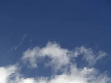 Dark bronze equestrian statue of Francisco Franco against a blue sky with scattered clouds.