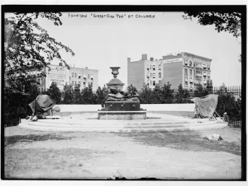The Great God Pan fountain with a reclining figure and central urn ornament in a grassy area.
