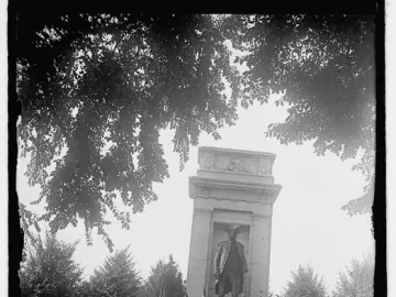 John Paul Jones Memorial with a statue of a uniformed man, surrounded by people in naval dress and flags during a ceremony.