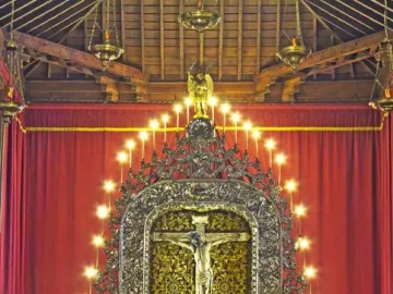 Cristo de La Laguna crucifix centered in an ornate gilded altar with lit candles and red curtains