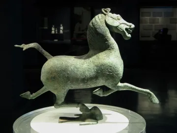 Flying Horse of Gansu bronze horse sculpture balanced on one hoof atop a bird on a display stand