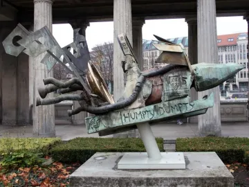 Humpty-Dumpty Machine bronze sculpture with green patina and machine-like components in front of a classical building