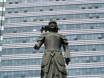 Marco Polo statue in ornate armor with a bird on his shoulder and a book in his hand