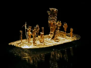 Muisca Raft gold miniature sculpture with small figures on a raft-like base against a black background