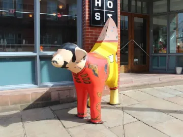 Superlambanana sculpture painted like a red uniform with gold details and a striped banana-shaped tail.