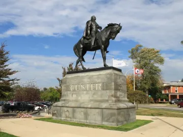 The Sighting the Enemy bronze equestrian monument of General Custer on a stone base with CUSTER carved on the front.