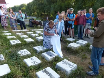 People gather around the Keyboard Monument while a woman unveils part of the installation with a white cloth.