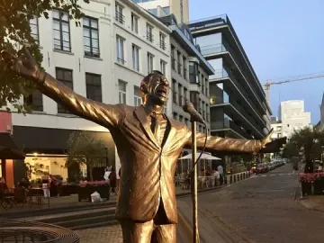 L\'Envol, a metallic statue of Jacques Brel with outstretched arms beside a microphone stand.