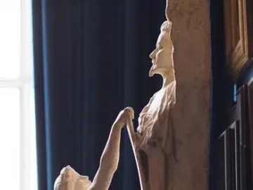 La Gloire, a nude figure pulling forcefully at a tall block that reveals a bearded man\'s profile.