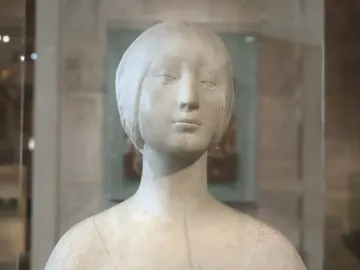 Pale marble bust of a young woman wearing a close-fitting headpiece