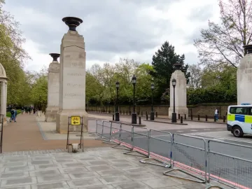 Commonwealth Memorial Gates with four stone pillars and urns along a paved street in London.