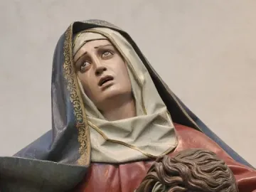 Pietà sculpture showing an anguished woman supporting the lifeless body of a bearded man with a bare torso.