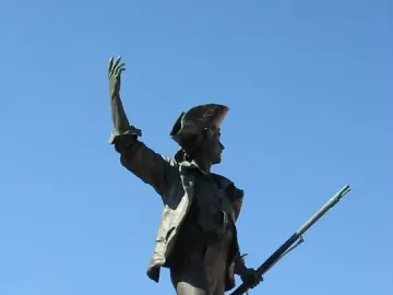 Statue of the Volunteer of 1792, a bronze soldier in a tricorne hat standing on a stone pedestal with one foot on a cannon.