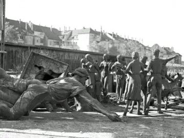 Bronze figures from the Youth Monument arranged among other disassembled statues, with some standing and others lying on the ground.