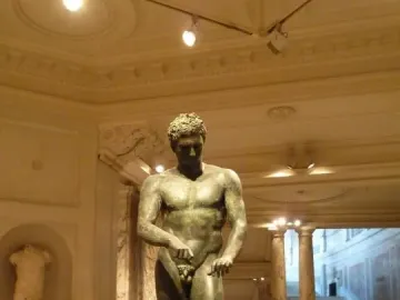 Athlete from Ephesus bronze statue displayed on a pedestal in a grand museum hall.