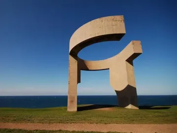 Elogio del Horizonte sculpture on a grassy hill above the ocean