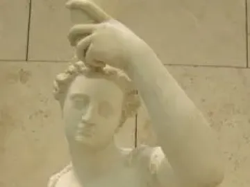 White marble female figure by Giambologna holding a small jug overhead while touching her foot, set on a stone column against a tiled wall.