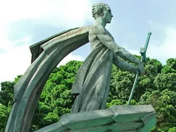 Monumento a Franco showing a green-patinated standing figure holding a staff above another stylized figure with an outstretched arm