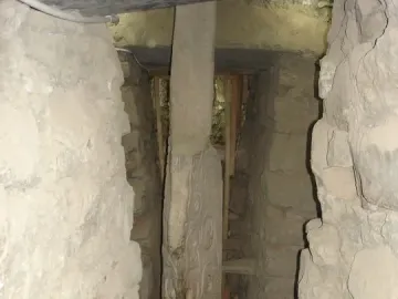 The Lanzón monolith standing in a narrow stone passage, with intricate carvings visible on its surface.