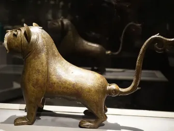The Lion of Monzon sculpture shown from a three-quarters angle, with engraved decorative patterns across its body.