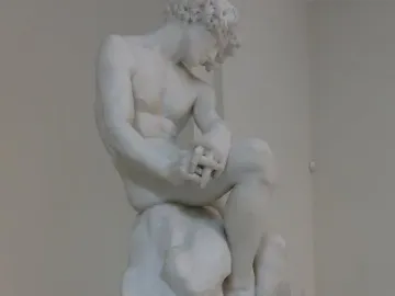The Exiled, a white marble statue of a seated nude man with bowed head and clasped hands.
