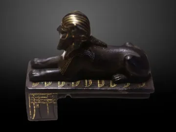 Thutmose III sphinx shown in profile with a gold-striped headdress and beard.