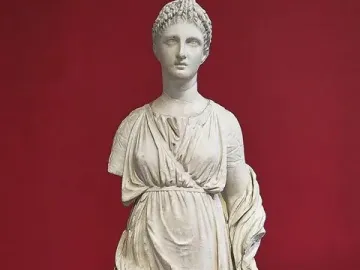 Artemis Diadoumena marble statuette with braided hair and draped garments, missing part of the left arm.