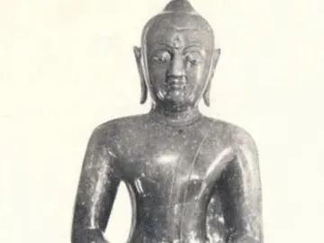 The Emerald Buddha seated on a simple base in meditative posture.