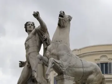Marble horse tamer statue with a rearing horse on a stone pedestal against a cloudy sky.