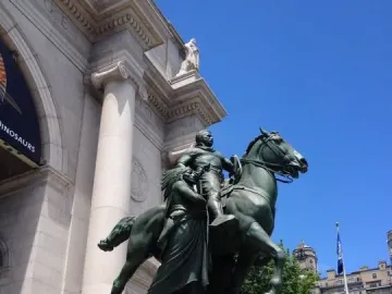Theodore Roosevelt Equestrian Statue in front of a grand museum building, with Roosevelt on horseback flanked by two walking figures.