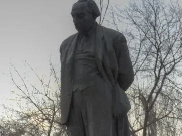 Monument to Avetik Isahakyan, a dark gray statue of a man in a suit on a stone pedestal