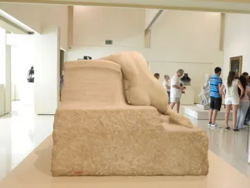 Desolation, a light stone sculpture of a reclining nude figure seen from the back on a rough rectangular base.