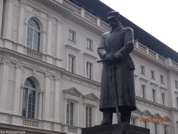 Józef Piłsudski Monument in front of a grand historic building with ornate windows and balconies.