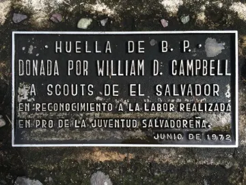 Rectangular plaque for B-P’s footprint with raised Spanish lettering, set into rough dark ground.