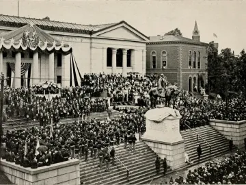 Charles Devens equestrian statue on a tall pedestal, surrounded by a large crowd during a public ceremony.