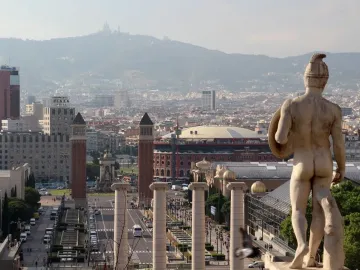 The Four Columns standing on Montjuic with a city street and buildings below.