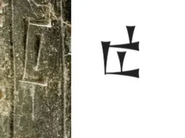 Close-up of the Iddi-Ilum statuette showing deeply incised cuneiform inscriptions on a dark stone surface.