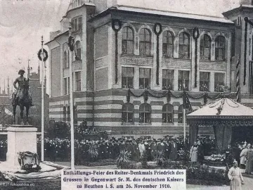 Equestrian Monument of Frederick the Great on a tall pedestal, with a crowd gathered around it and flagpoles nearby.