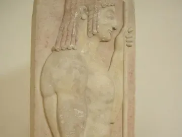 Grave stele relief of a youthful male figure in profile holding a staff against a red background.