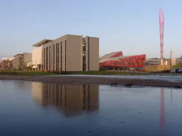 Aspire, a tall red lattice steel sculpture, rises beside a partially frozen lake.
