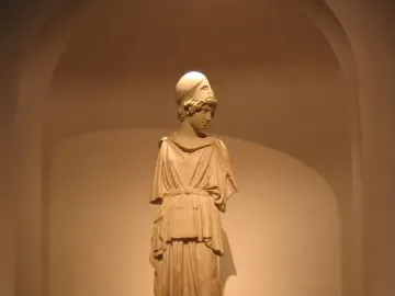 Draped statue of Athena wearing a helmet, standing on a dark pedestal in a recessed arched alcove.