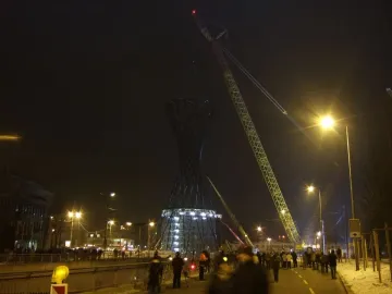 The Mae West sculpture stands lit at the base as a crane rises above it during nighttime construction.