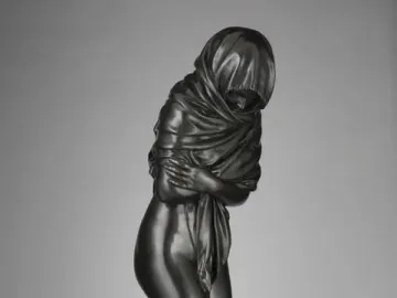 Winter, a dark bronze female figurine wrapped in heavy drapery and standing on a circular base.