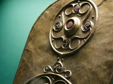 The Battersea Shield with two circular bosses and intricate swirling bronze patterns.