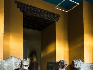 Four Sam\'al lion sculptures displayed on pedestals in a museum gallery.