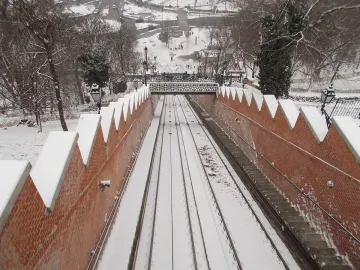 Snow-covered funicular railway descending between brick walls on Buda Castle Hill.
