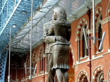The Meeting Place bronze sculpture of a man and woman embracing inside a large vaulted hall.