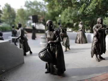 Virginia Women\'s Monument sculptures of women in period clothing on a stone plaza surrounded by trees.