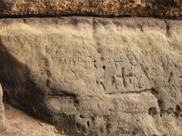 Devil\'s Heads sandstone carving with a bearded face and etched symbols across the rock surface.