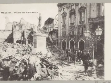 The statue of John of Austria stands on a tall pedestal amid earthquake rubble in a devastated square, with several people nearby.